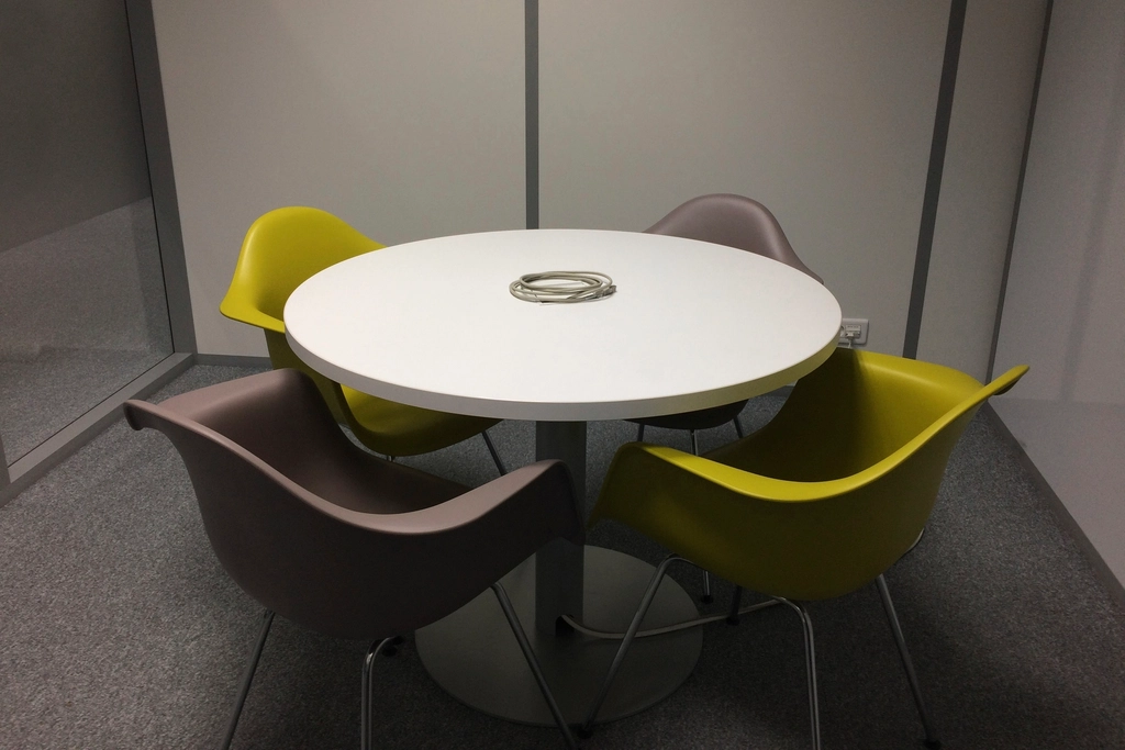 A small meeting room with a round white table and four chairs