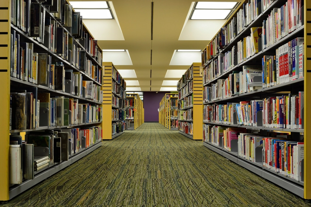 An aisle between tall bookshelves in a university library